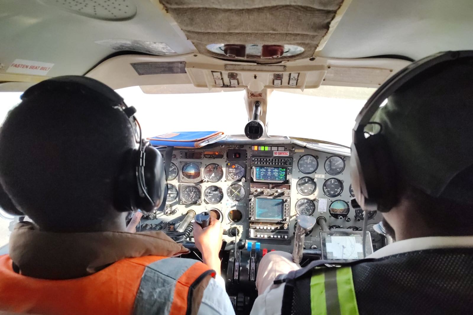 Two pilots in headsets at the controls of a twin-engine aircraft